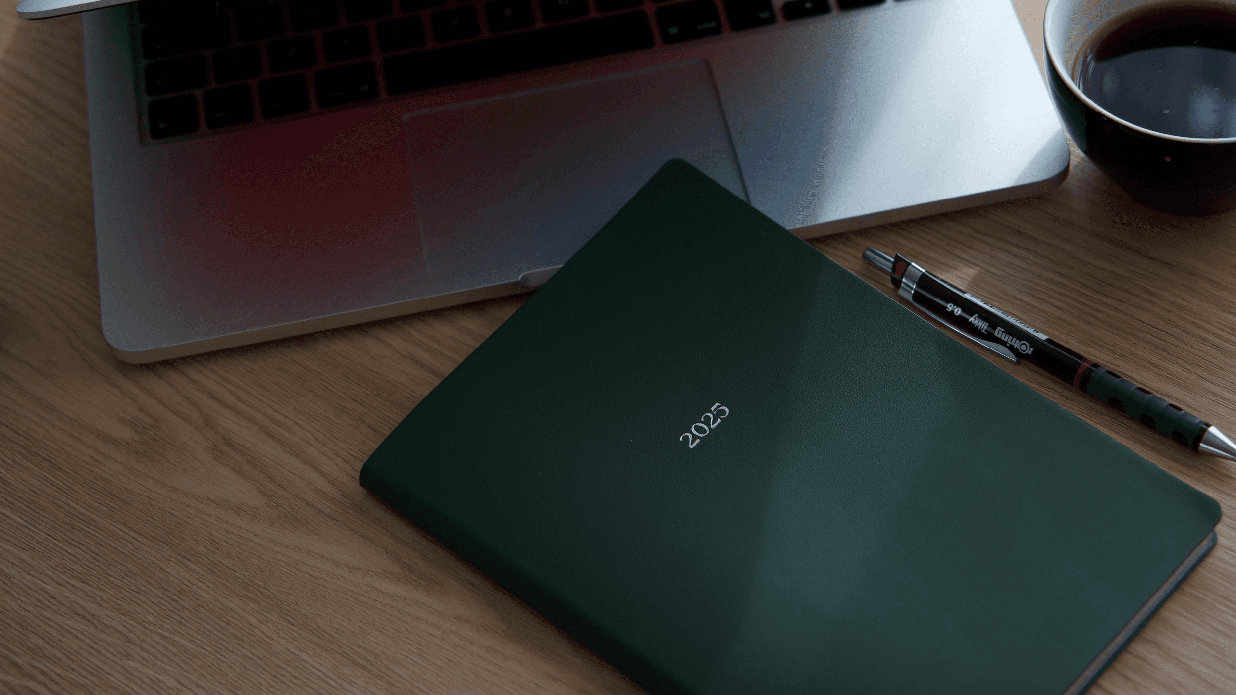 Minimalist workspace with laptop, planner, and coffee